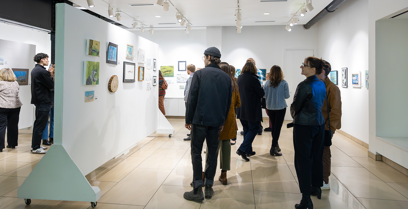 A photo of a group of people viewing artwork hanging on walls.